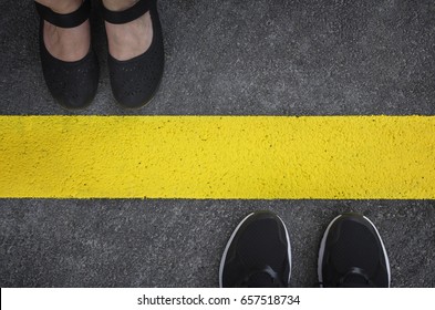 Beine eines Paares, die sich gegenüberstehen, geteilt durch die gelbe Asphaltlinie Draufsicht