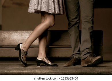 Legs of a couple standing while her is kissing him.