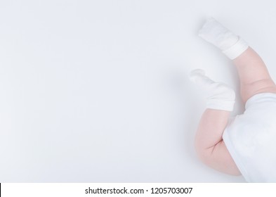 Baby’s legs. Crawling baby in white socks and bodysuit. View from above. Copy space.