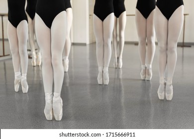 Legs of a dancer on white pointer shoes in the choreographic hall. Young ballerina