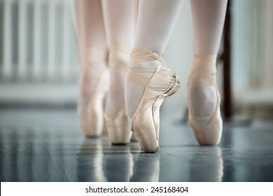 Legs dancers on white pointe, near the choreographic training machine. Young ballerinas.
