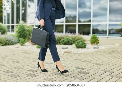 Legs detail of business woman on the way to office, walking outdoors holding a laptop case, wearing business suit and high heels, looking meet boss or colleagues, planning interview with hr manager - Powered by Shutterstock