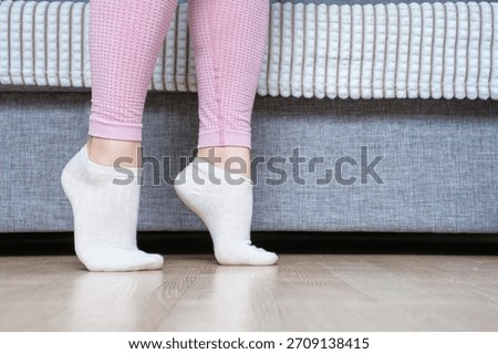 Legs doing exercises lifting on toes close-up, home workout concept.