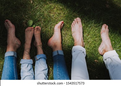 Legs of father, mother and daughter lying on green grass. Family concept