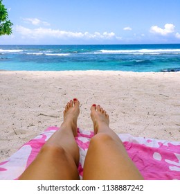 Legs And Feet With Fake Spray Tan And Painted Toenails On Sun Lounger On Tropical Beach With Pink Towel At Lefaga, Upolu Island, Western Samoa, South Pacific