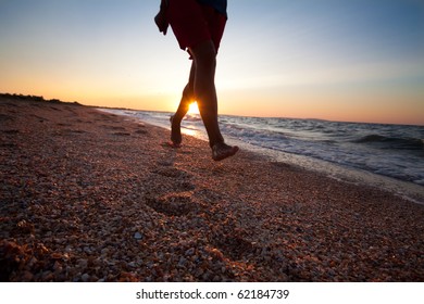 Legs And Feet Of Man Running At The Beach On Beautiful Summer Sunset