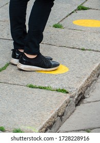 Legs And Feet Of A Person Waiting In Line And Standing Inside Yellow Circles With Social Distancing Measures Pandemic Outbreak.