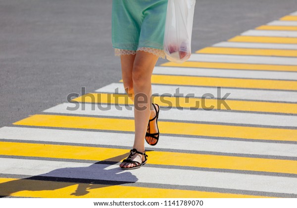 Legs of a\
girl crossing the road through a\
zebra