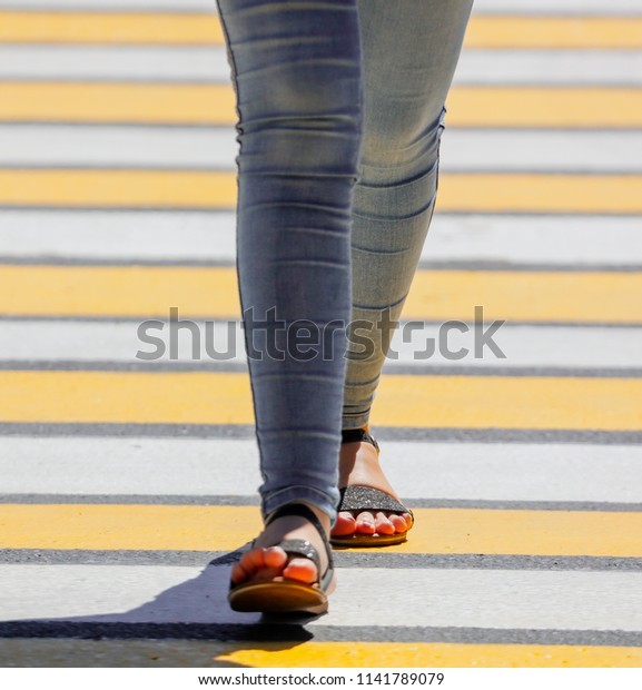 Legs of a\
girl crossing the road through a\
zebra