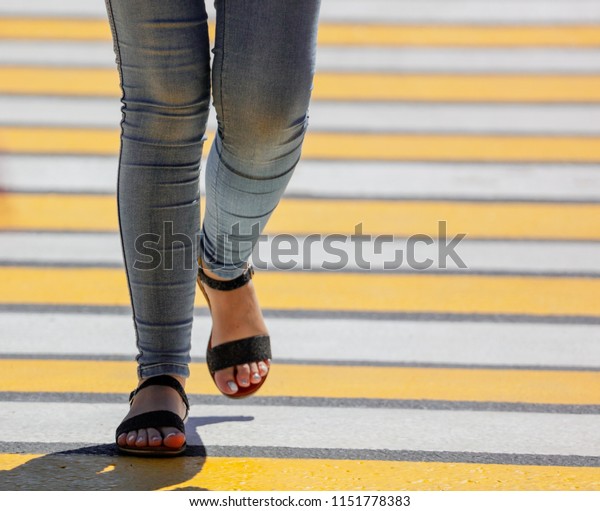 Legs of a\
girl crossing the road through a zebra\
.