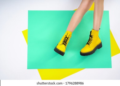  Legs Of The Girl In Yellow Leather Shoes On A Green Background. Fashion Photography Fashionable Lookbook New Shoe Collection Autumn Winter                              