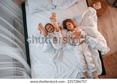 Similar – Mother reading book to her sons in the bed