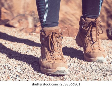 Legs in high hiking boots of coyote color with a textured sole close-up, a girl walks along a path in the mountains, rocky terrain in comfortable shoes for active pastime in a daytime. - Powered by Shutterstock