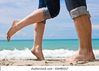 legs of kissing couple on beach