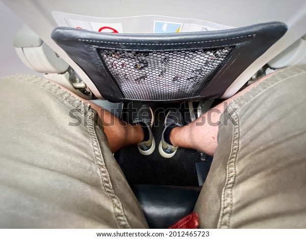 The\
legs of a man sitting in an airplane. Economy class and narrow\
spaces between the seats. Sports and summer\
clothing.