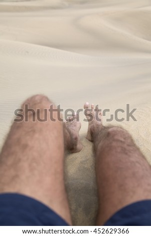 Legs of a man walking and leaving foot print on the sand