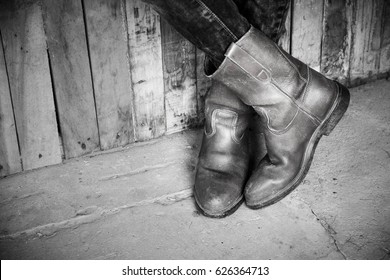 Legs of man wearing boots standing in barn,Black and white