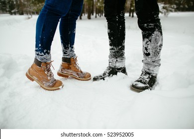 Legs Man And Woman In Winter Boots Standing In The Snow Next To Each Other.