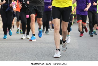 Legs Of Many Runners At Footrace On The Road Of The City