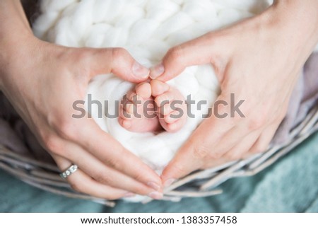 Legs newborn baby and Mama's arms heart