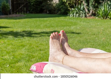 The Legs Of An Old Woman Laying Down And Sunbathing In The Garden