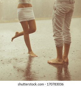 Beine am Strand. Fußbad. Ein liebendes junges Ehepaar umarmt und küsst unter einem Regen. Zwei Liebhaber, Mann und Frau barfuß in der Dusche. Sommer in Liebe