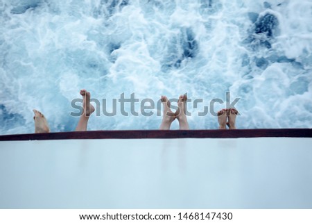 Legs on the fence of the ship sailing in a summer day on vacation holiday against a blue sea. Relaxing on cruise ship