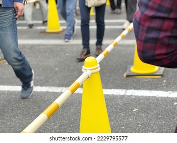Legs of people in line, yellow cones and bars - Shutterstock ID 2229795577
