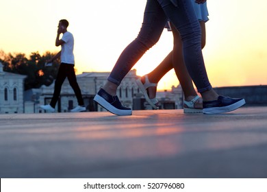 legs of people walking at sunset