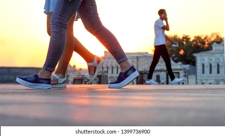 legs of people walking at sunset. Leisure and recreation in the city