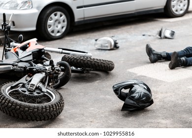 Legs of a person lying on the road after a motorcycle and car accident