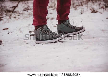 the legs of a person standing on the snow path at winter close up
