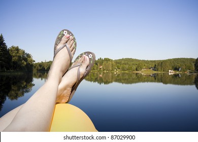 Legs Resting On A Paddle Boat In Calm Lake Water Shot In Muskoka Cottage Country Ontario