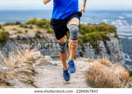 legs runner man in knee pads running mountain trail, protection knee sleeve after injury to stabilization legs