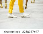 legs of a sambista dancing, with yellow pants and white shoes at the sambodromo da marques de sapucai in Rio de Janeiro, Brazil.