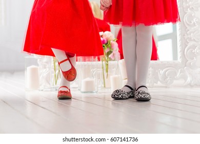 Legs in shoes two little girls in red dresses