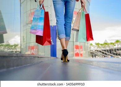 legs of slender woman happy and joyful in shopping mall center, buying and shopping consumerism with many bags holding in both hands