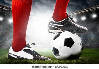 legs of a soccer or football player on ball on stadium