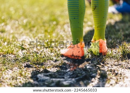 Legs of Soccer Player Standing in Muddy Grass Pitch. Football Clothes Covered With Mud. Junior Level Football Game in Rainy Day