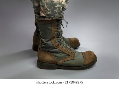 Legs of a soldier in camouflage and army boots on a gray background. Military conflicts and crises. Close-up. 