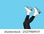 Legs of sporty young woman in ice skates on blue background