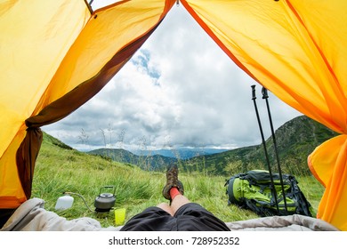 legs of the traveler in hiking boots in a tent outdoors