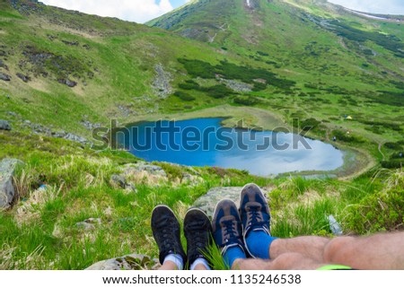 Legs of traveler sitting on high mountain top in travel. Freedom concept