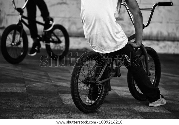 自然の背景に屋外で接写した夏のスポーツアクティビティ 横の写真の通り オレンジと黒の低自転車に座る2人の10代の少年の脚 の写真素材 今すぐ編集