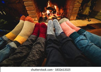 Legs View Of Happy Family Lying Down Next Fire Place Wearing Warm Wool Socks - Main Focus On Right Woman Feet