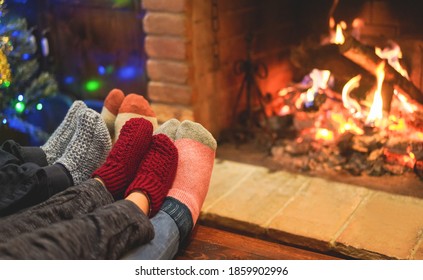 Legs View Of Happy Family Wearing Warm Socks In Front Of Fireplace - Winter, Love And Cozy Concept - Focus On Pink Woolen Socks