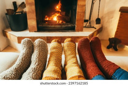 Legs view of happy family wearing warm socks in front of fireplace - Winter, love and cozy concept - Focus on center socks - Powered by Shutterstock