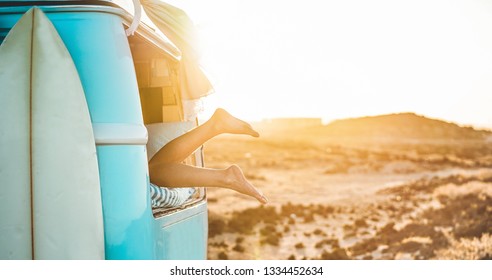 Legs view of happy surfer girl inside minivan at sunset - Young woman having fun on summer vacation - Travel,sport and nature concept - Focus on feet - Powered by Shutterstock