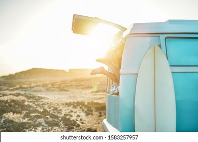 Legs view of happy surfer girl inside vintage minivan at sunset - Young woman having fun on summer vacation - Travel,sport and nature concept - Focus on feet  - Powered by Shutterstock