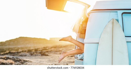 Legs view of happy surfer girl inside minivan at sunset - Young woman having fun on summer vacation - Travel,sport and nature concept - Focus on feet - Warm contrast filter - Powered by Shutterstock